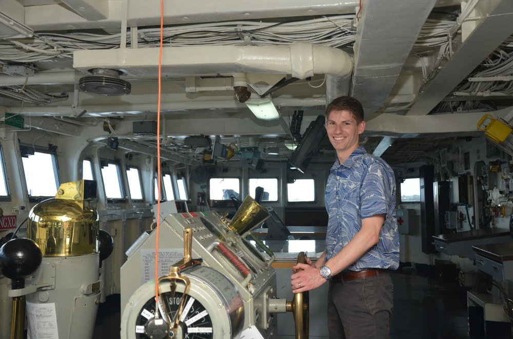 Will Rogers, a military legislative assistant, poses with the helm of USS Frank Cable (AS 40) during a Congressional tour