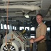 Maj. Christopher Shore, member of the Joint Program Office Forward, poses with the helm of USS Frank Cable (AS 40) during a Congressional tour