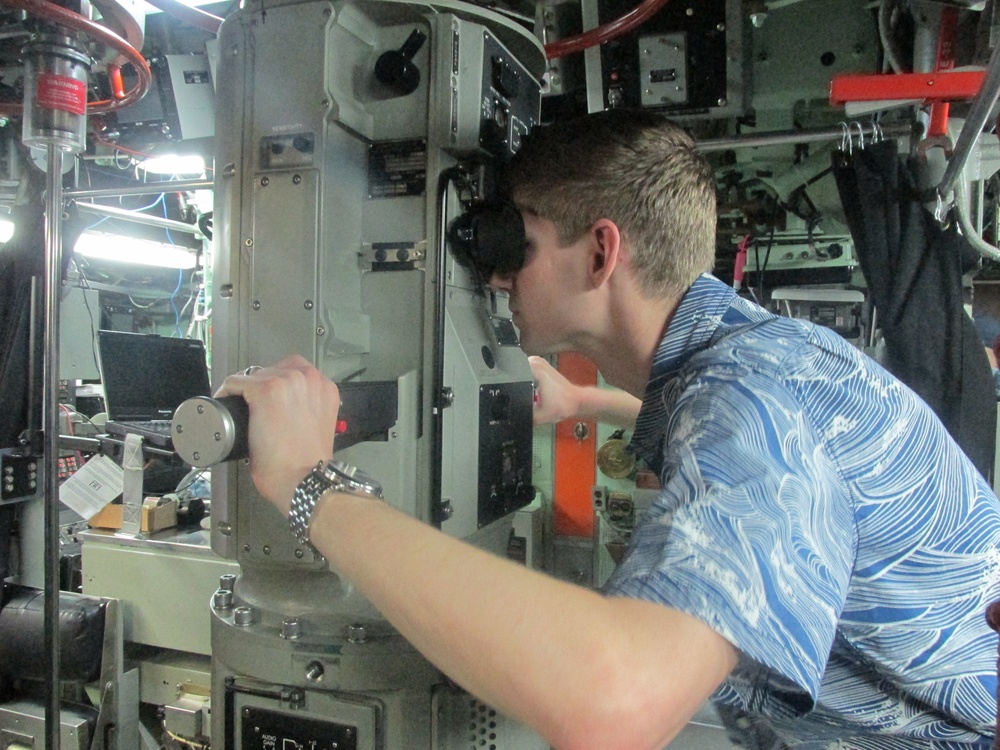 Will Rogers, a military legislative assistant, looks through the periscope of USS Topeka during a Congressional delegation tour