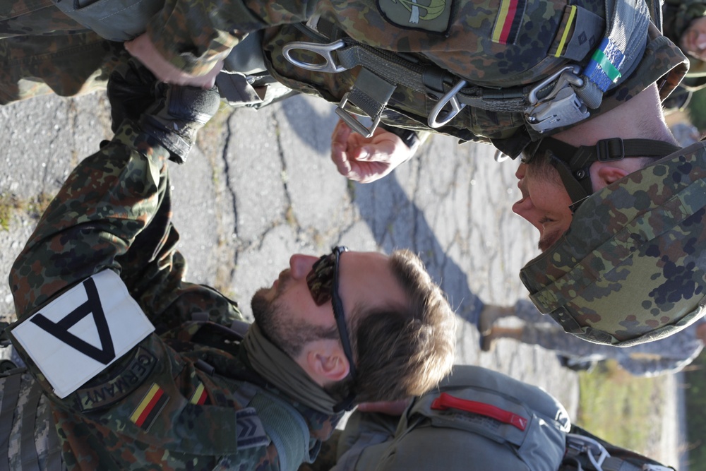 German Jumpmaster assists a paratrooper