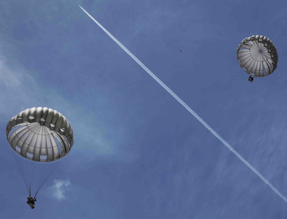 Paratroopers descend onto an airfield.
