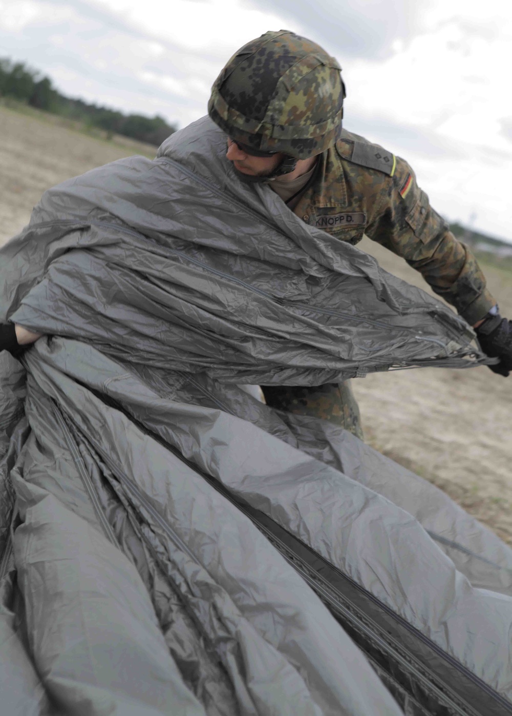 German soldier preps parachute for packing.