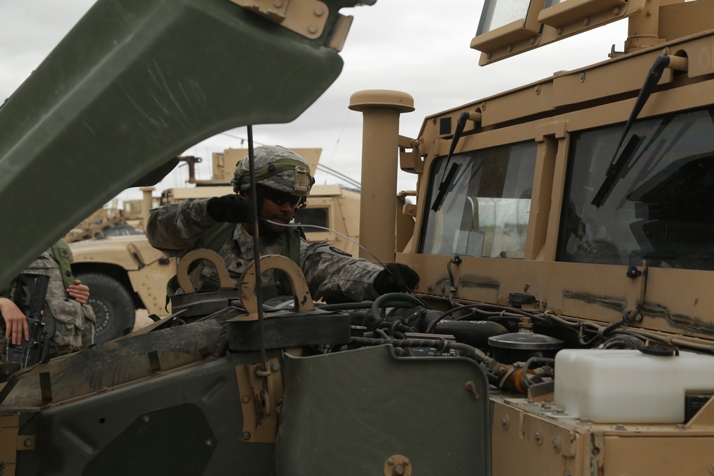 Soldier performs maintenance checks and services on a Humvee