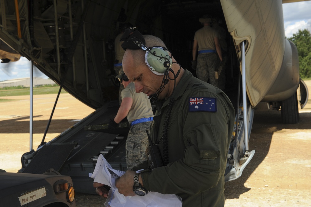 RAAF Airmen work with USAF Airmen to upload Humvee