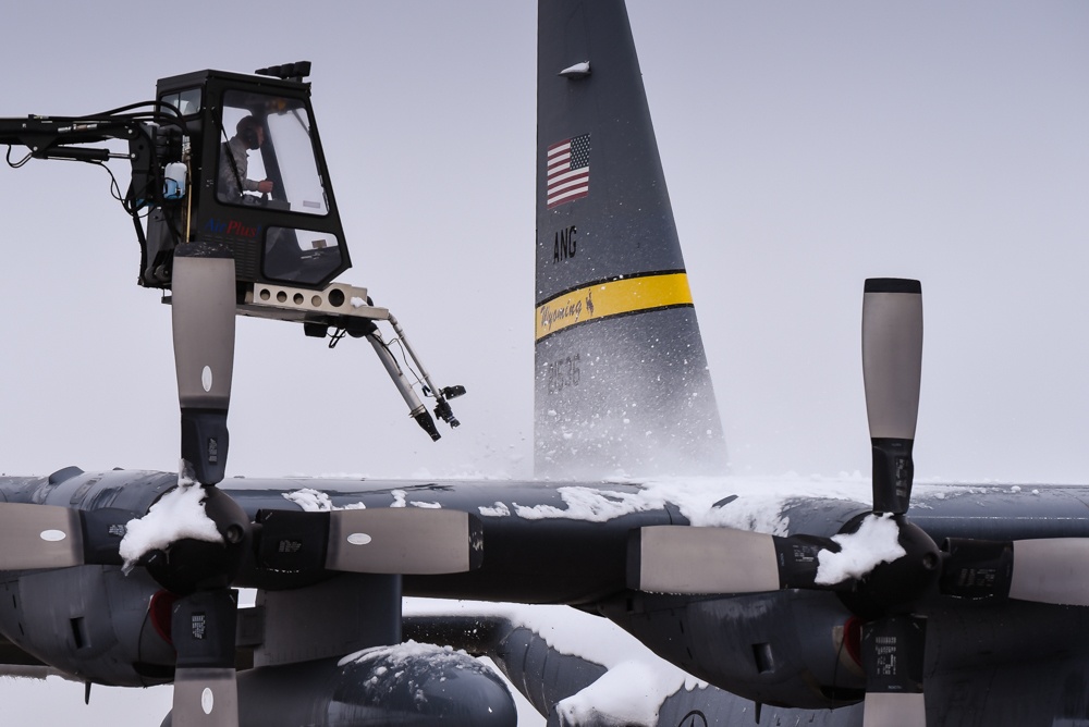 Airmen remove snow from aircraft after late Spring snow
