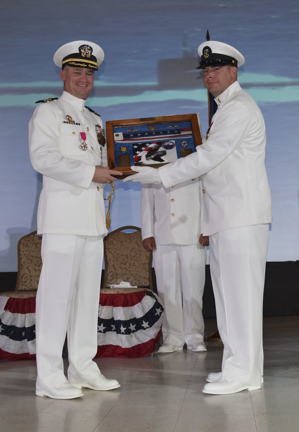 Master Chief Machinist Mate (Auxiliary) Jamie Manzoeillo presents Cmdr. Lance Thompson with his commissioning pennant during the USS Chicago change of command ceremony May 12