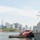 A U.S. Navy guided-missile destroyer named 'FARRAGUT' is visible on the right side of the image, accompanied by a red tugboat alongside it in the harbor. The scene is set against the iconic Manhattan, New York City skyline, with One World Trade Center prominently visible in the background. A small island with historic brick buildings, consistent with Governors Island, is visible in the middle ground.