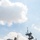 The image shows a large US Navy warship docked in an urban harbor, likely during a public event such as Fleet Week. The vessel displays the number '5' on its island superstructure and has multiple radar and communications arrays visible. Several uniformed personnel are standing on deck, with city skyscrapers visible in the background.