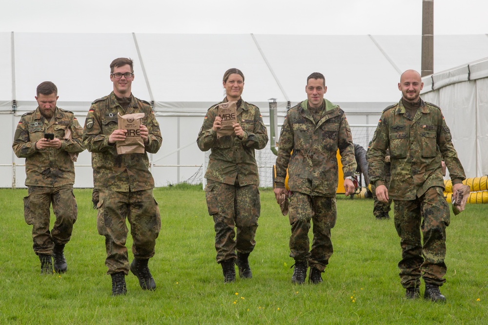 U.S. Army soldier gives MREs to a German Soldiers waiting for transportation