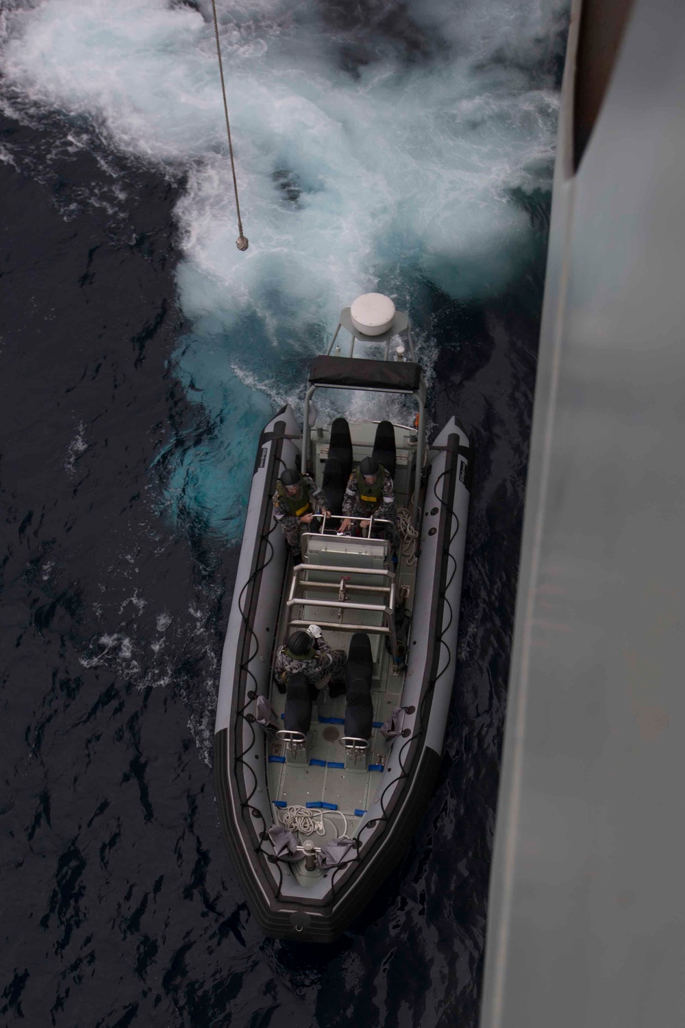 Australian sailors launch a rigged hull inflatable boat off HMAS Adelaide