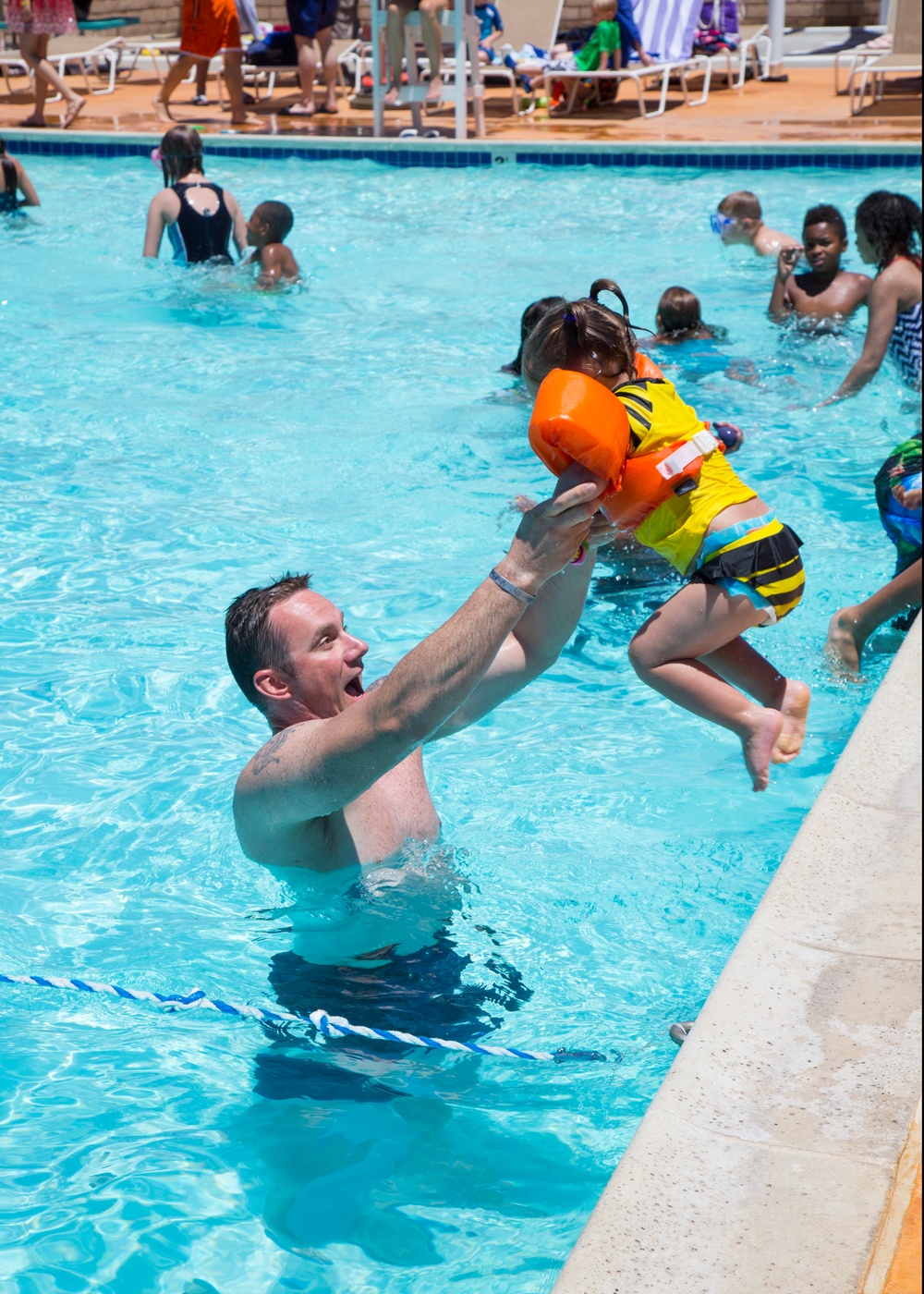 Army Chief Warrant Officer 2 Bryan Crumpler catches his daughter, Quinn, age 2, as she leaps from the edge of the pool during the Marine Corps Community Services All American BBQ at the Oasis Pool and Water Park aboard Marine Corps Logistics Base Barstow,