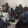 Crisis Response Marines conduct Intelligence training with Ghanaian Forces A group of military and uniformed personnel are gathered around computer workstations in what appears to be a training or operations room. One individual in camouflage uniform, likely a Western military advisor, is engaged in discussion with several personnel wearing light blue uniforms, suggesting a joint training or advisory session. The setting appears to be a computer lab or command center environment.