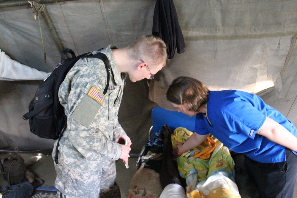 United States Military Academy cadet observes as Army Reserve nurse checks on patient at Chad hospital