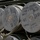 Fighting our nation's wars: one 50lb round at a time The image shows multiple stacked cylindrical military ammunition containers, specifically 120mm cartridges. The containers are marked with designations indicating they are TPCSDS-T M865 training rounds. They are stored in what appears to be a military storage or transport configuration.