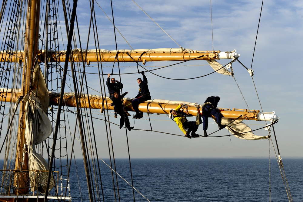 Coast Guard Cutter Eagle crewmembers repair damaged sails while underway