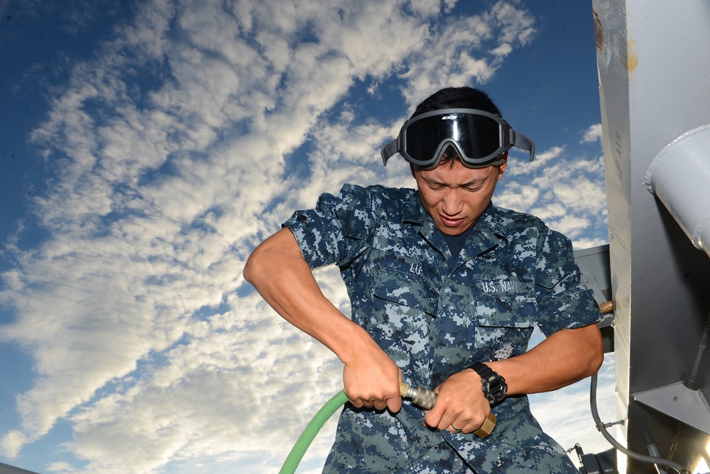Airman Bo Lu, a Chinese immigrant,, tightens an air hose fitting aboard the amphibious assault ship USS Bataan (LHD 5).