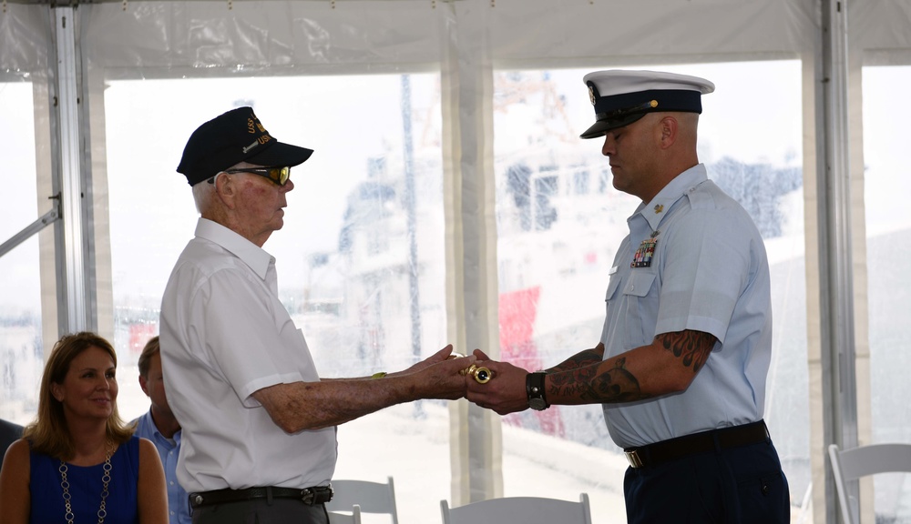 Walt Slater, U.S. Navy Retired Motor Machinist's Mate 3rd Class, presents the ship's long glass to Petty Officer 1st Class Robert Stous, crewmember and plankowner, during the commissioning ceremony of the 18th Fast Response Cutter.