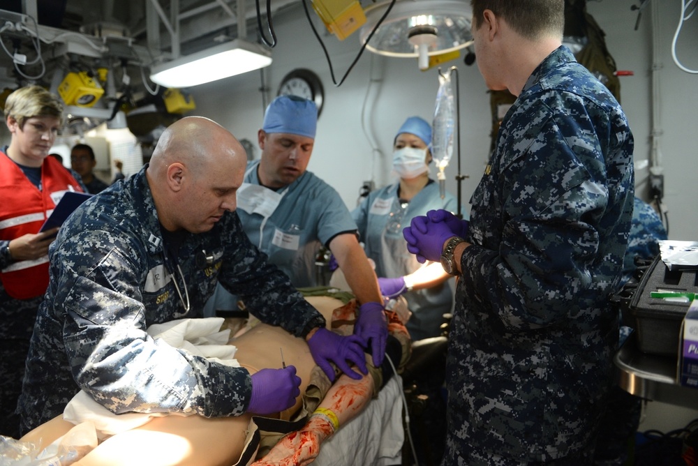 Sailors assigned to the amphibious assault ship USS Bataan (LHD 5), Fleet Surgical Team 6 and Naval Medical Center Portsmouth work together to give medical care to a simulated patient during a mass casualty drill in medical triage aboard Bataan.