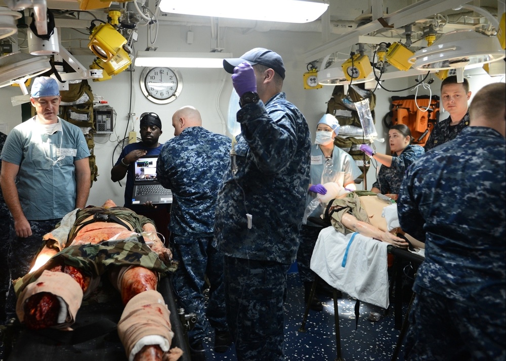 Sailors assigned to the amphibious assault ship USS Bataan (LHD 5), Fleet Surgical Team 6 and Naval Medical Center Portsmouth work together to give medical care to a simulated patient during a mass casualty drill in medical triage aboard Bataan.