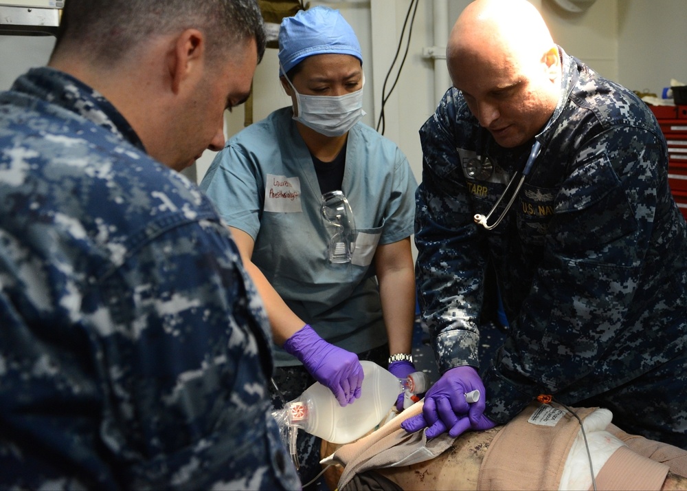 Sailors assigned to the amphibious assault ship USS Bataan (LHD 5), Fleet Surgical Team 6 and Naval Medical Center Portsmouth work together to give medical care to a simulated patient during a mass casualty drill in the medical triage aboard Bataan.