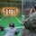 USAG Benelux Soldiers qualify with brand new M4A1 carbines. Two military personnel are at an indoor shooting range. One soldier in digital camouflage (ACU pattern) is in the prone position aiming downrange, while a second soldier in multicam/OCP pattern uses binoculars to observe the targets. The facility features multiple illuminated target frames at the far end of the range.