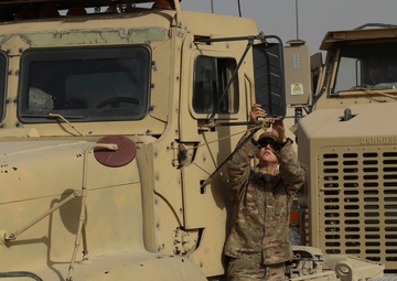 Soldier cleans mirror on her M915A3 truck