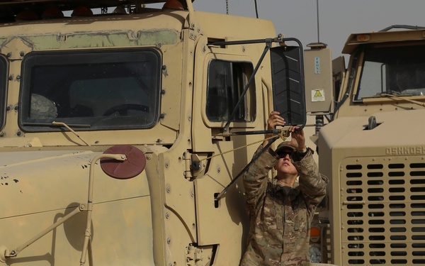 Soldier cleans mirror on her M915A3 truck