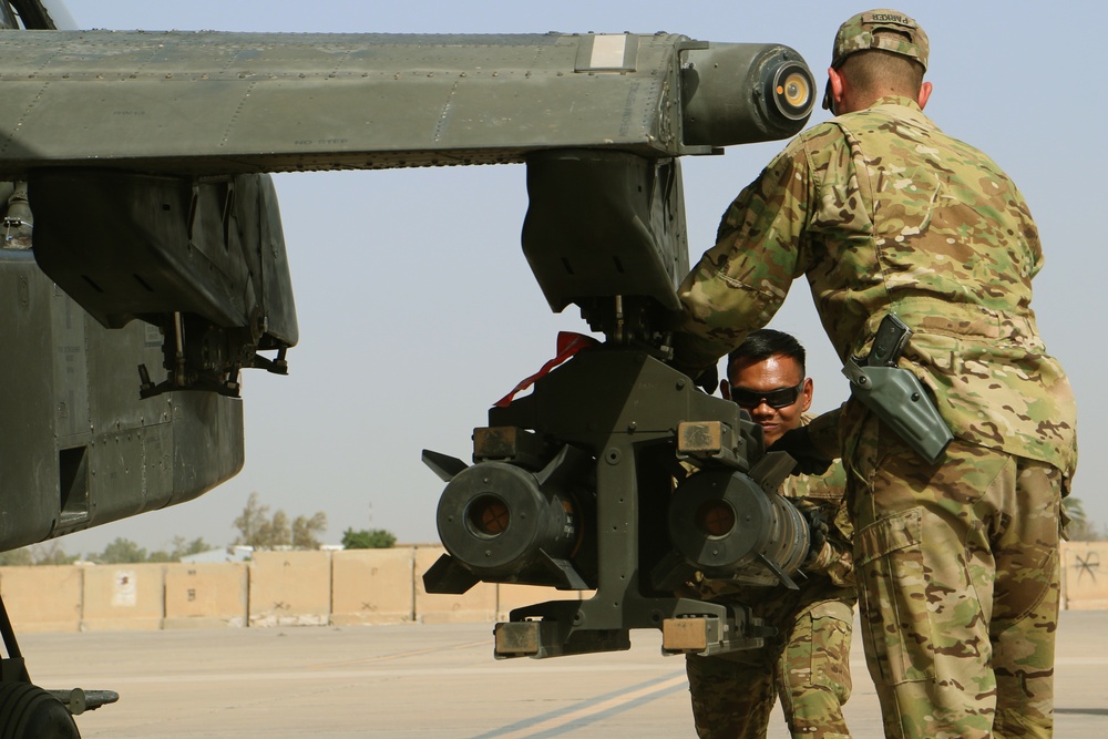 Soldiers load rockets, missiles on Apache attack helicopter
