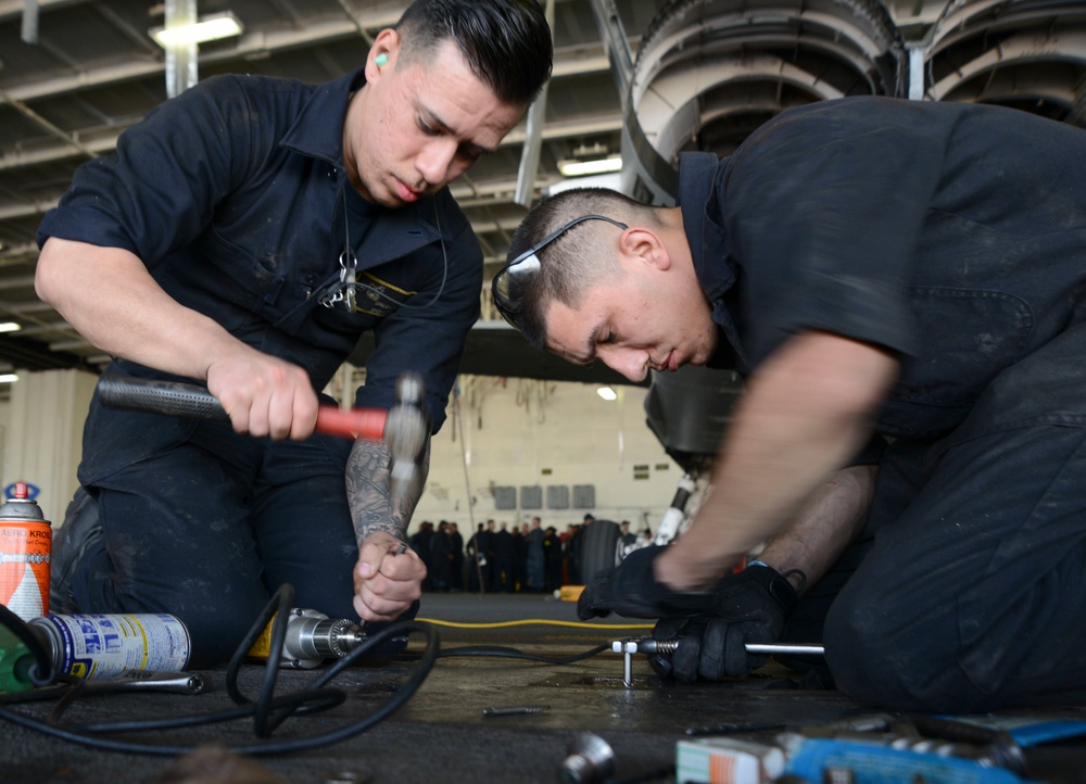 Sailors conduct maintenance on hanger door track