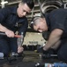 Sailors conduct maintenance on hanger door track