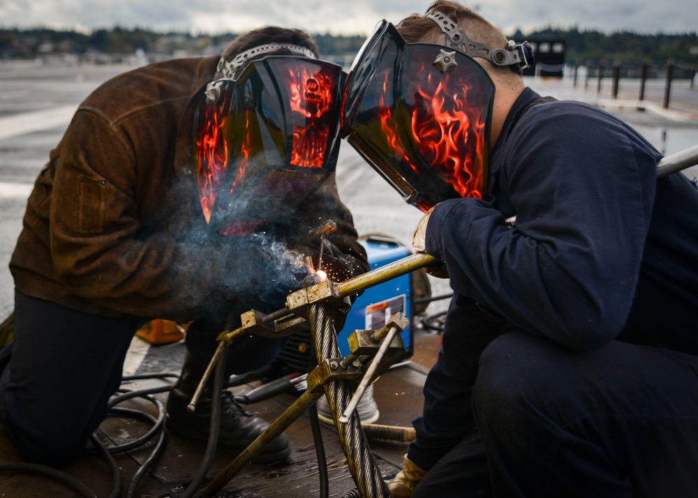 Sailors weld arresting cable