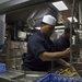 USS Zumwalt Sailors clean dishes in the ship's scullery