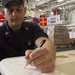 USS Zumwalt Sailor signs a board for presentation to ship's sponsor family