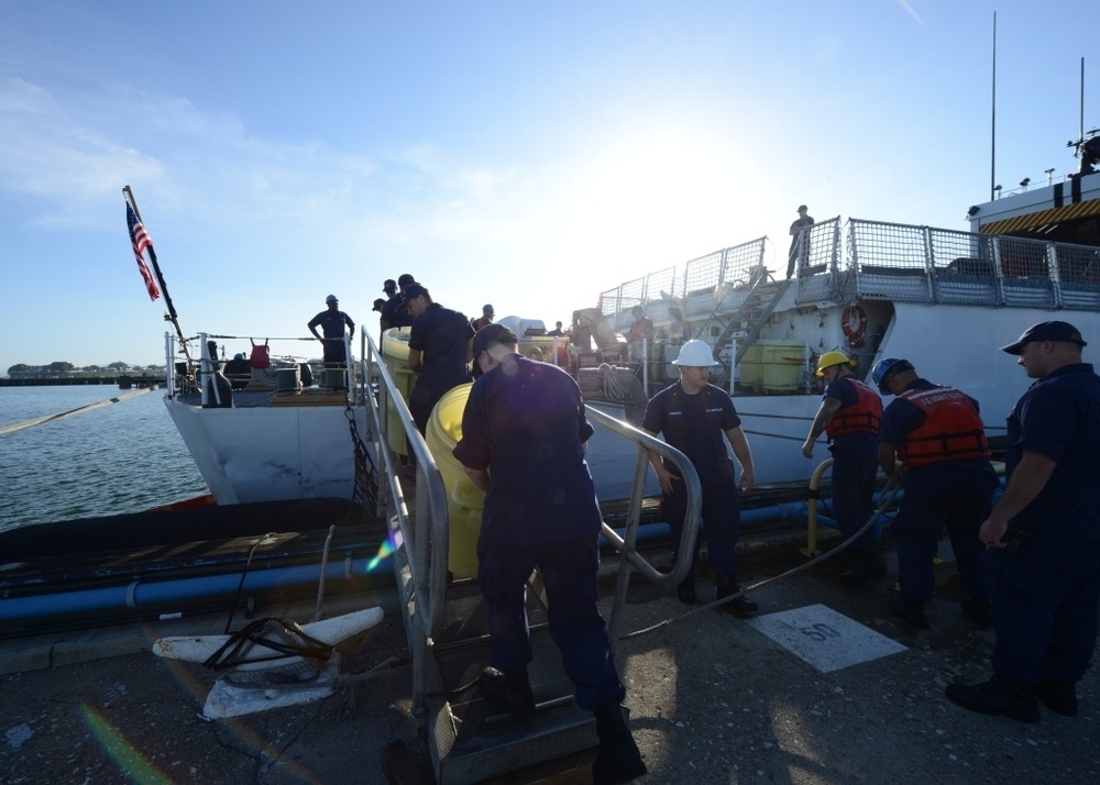 Crew members aboard the Coast Guard Cutter Spencer bring trash cans ashore to empty them after being underway.