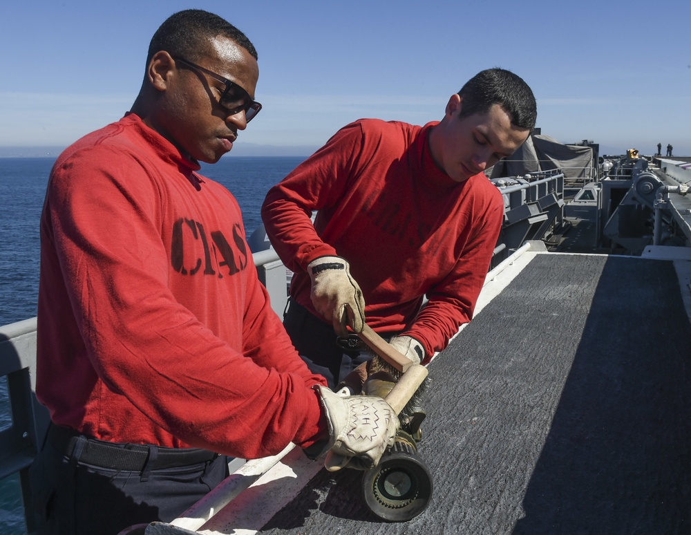 Sailors conduct maintenance on a firefighting equipment