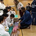 Williams and Burkett Hand Out Snacks to Japanese Children