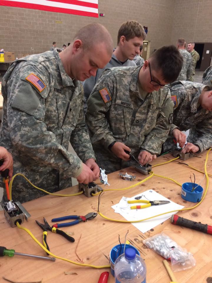 Spc. Johnathan A. Arnold, left, and Pfc. Dylan B. Berger wire a three-way switch