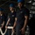 The aircraft carrier is deploying as part of the George H.W. Bush Carrier Strike Group in support of maritime security operations and theater security cooperation efforts in the U.S. 5th and 6th Fleet areas of operations Three naval personnel in dark blue uniforms and blue hard hats are handling a large white mooring line aboard what appears to be a U.S. Navy vessel. A fourth crew member is visible in the background near equipment controls. The scene depicts a line-handling evolution, likely during a mooring or underway replenishment operation.