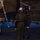 Lightning II strikes Iwakuni, F-35B arrives Two military personnel in flight suits are interacting beside a military jet aircraft at night on a flight line. The aircraft is marked with 'VMFA-121', identifying it as belonging to Marine Fighter Attack Squadron 121. One individual appears to be wearing a flight helmet with visor, suggesting a pilot preparing for or returning from a mission.