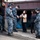 USS Bonhomme Richard (LHD 6) Sailors participate in a Food Drive A group of U.S. Navy personnel in blue digital camouflage uniforms are interacting with two civilian women, likely in Japan or another East Asian location. One of the civilian women has her hands pressed together in a gesture of gratitude or greeting. The scene appears to depict a community relations or humanitarian assistance interaction.