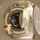 170123-N-TI693-051 The image is taken through a circular hatch or porthole, revealing the interior of what appears to be a hyperbaric chamber or pressure vessel facility. Multiple interconnected cylindrical chambers are visible, with a person wearing a dark shirt with 'NEDU' text standing inside. The perspective creates a tunnel-like effect through several circular openings.