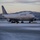 Boots in the Snow A United Airlines Boeing 747 wide-body aircraft is taxiing on a snow-covered runway or taxiway during winter conditions, likely at dusk or dawn based on the low ambient light. The aircraft displays the United Airlines livery with the globe logo on the tail fin. Snow-dusted mountains are visible in the background, suggesting a mountainous airport location.