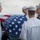 170117-N-BL637-077 A military burial at sea ceremony is being conducted by U.S. Navy sailors in dress white uniforms. A flag-draped casket is being held by pallbearers on what appears to be the deck of a naval vessel, with open ocean visible in the background. The scene depicts a solemn and formal funeral honors ceremony.