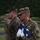 Defense POW/MIA Accounting Agency Disinterment Military personnel from multiple branches are participating in a formal ceremony, with a U.S. Army soldier in the foreground holding a folded American flag while wearing white ceremonial gloves. Behind him stands a U.S. Marine in MARPAT camouflage, and additional service members are visible in the background. The solemn expressions and precise flag-folding suggest this is a military honors or memorial ceremony.
