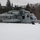 HMH-464 Marines Conduct Flight Operations during Exercise Frigid Condor A U.S. Marines heavy-lift helicopter, marked with the number '57' and 'MARINES' on the fuselage, is landed on a snow-covered field. The aircraft appears to be a Sikorsky CH-53E Super Stallion in a gray paint scheme. The setting is a winter environment surrounded by bare deciduous and evergreen trees under an overcast sky.