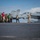 170123-N-MJ135-154 A group of military personnel in mixed uniforms are walking in a line along the flight deck of a US Navy aircraft carrier. Two F/A-18 Hornet/Super Hornet jets are visible in the background, marked with modex numbers 304 and 407. The scene appears to be a guided tour or inspection walkthrough on the carrier deck.