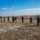 Task Force Southwest Marines prep for Afghanistan deployment A group of military personnel are conducting a live-fire shooting range exercise in an open field. Multiple soldiers in combat gear are positioned along a firing line facing a row of blue-and-white human silhouette targets. The setting appears to be a flat, arid training range under clear blue skies.