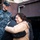 USS Bonhomme Richard (LHD 6) Sailors participate in a Food Drive An emotional scene showing a middle-aged Asian woman in a beige jacket embracing another person, with tears visible on her face. Two individuals in U.S. Navy digital camouflage uniforms and caps are present in the background, one smiling warmly. The setting appears to be outdoors near a building.