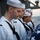 170117-N-BL637-038 U.S. Navy sailors assigned to USS Carl Vinson are participating in a burial at sea ceremony aboard a naval vessel. The sailors are dressed in white service uniforms and are standing in a solemn formation with heads bowed, alongside a casket draped in an American flag. The ocean is visible in the background, consistent with an at-sea military funeral ceremony.