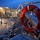 170120-N-OH262-432 A twilight or early morning photograph taken aboard a vessel, featuring a prominent orange life preserver ring mounted on aluminum railings. The life ring displays partial text reading 'UNS' and 'CARSON CITY', suggesting this is a U.S. Navy ship named USS Carson City. The deck area shows metal staircases, a cable reel, and dock lighting visible in the background.